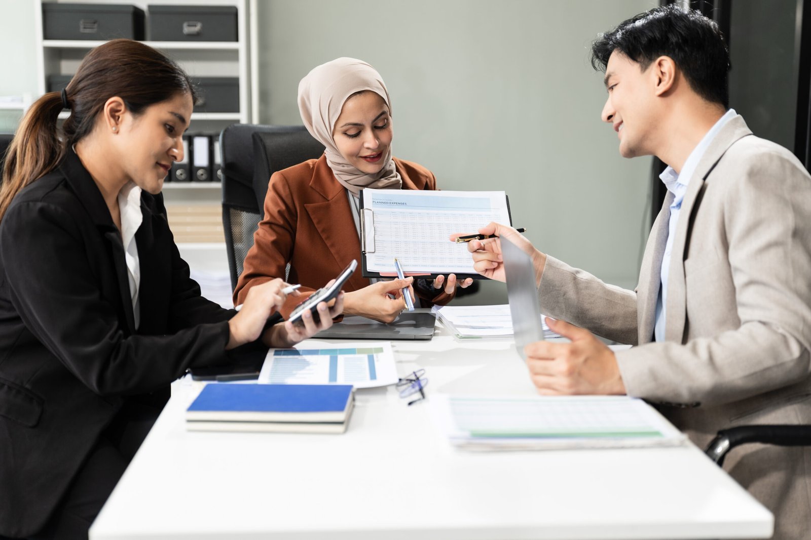 Business team using a calculator to calculate the numbers of statistic business profits growth rate on documents graph data, desk in the office.
