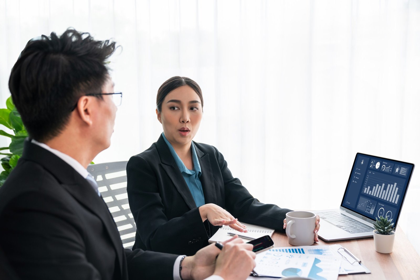 Busy analyst team in office discuss data analysis and marketing strategy using BI dashboard and statistics on laptop screen to improve business performance at meeting with strong teamwork. Jubilant