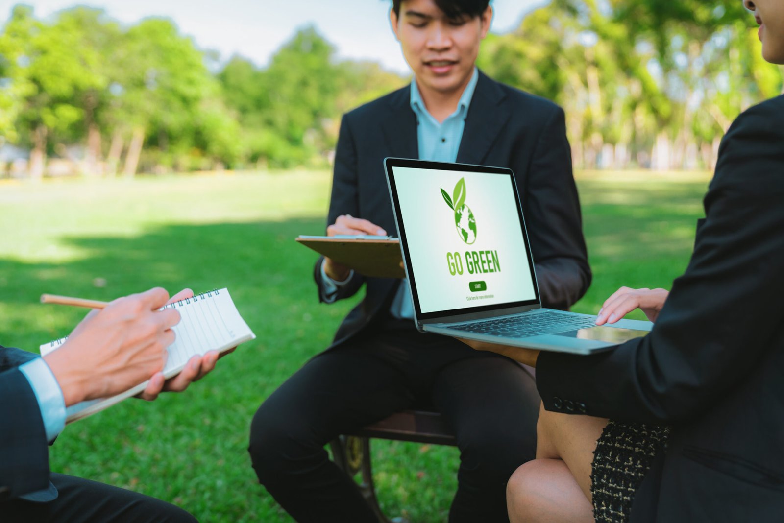 Group of asian business people planning on environmentally friendly development plan on laptop screen and sustainable technology project for greener future, outdoor eco office at natural park. Gyre